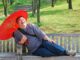 WHO-Empfehlungen: Ein lachender Mann sitzt unter einem Sonnenschirm auf einer Parkbank