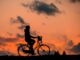 Frau auf dem Fahrrad vor Sonnenuntergang