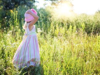 Ein Mädchen steht auf einer Sommerwiese